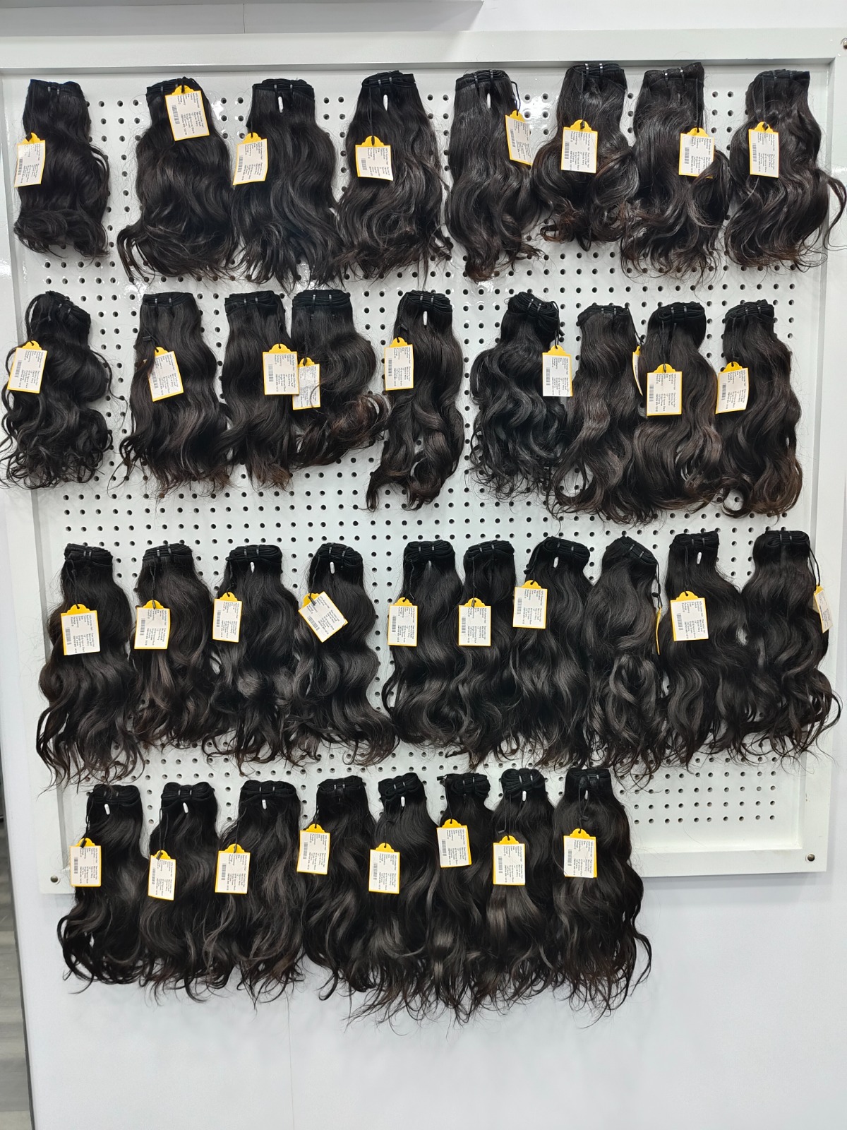 Raw Indian hair vendors: wavy virgin Remy hair bundles on a display wall at Tirumala Hair